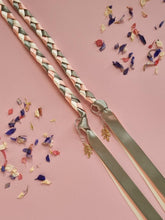 Load image into Gallery viewer, Intertwined Handfasting Cord made from cream, sage and peach coloured strands of satin ribbon, along with gold leaf charms. Set against a pink backdrop with confetti.