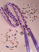 Load image into Gallery viewer, Intertwined Handfasting Cord made from mauve, lilac and lavender strands of satin ribbon, along with silver tree of life charms. Set against a pink backdrop with confetti.