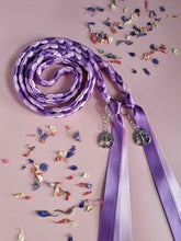 Load image into Gallery viewer, Intertwined Handfasting Cord made from mauve, lilac and lavender strands of satin ribbon, along with silver tree of life charms. Set against a pink backdrop with confetti.