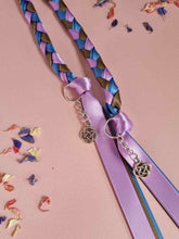 Load image into Gallery viewer, Intertwined Handfasting Cords made from mauve, blue and green strands of satin ribbon, along with silver celtic knot charms. Set against a pink background with confetti.