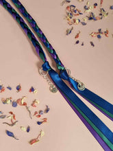 Load image into Gallery viewer, Intertwined Handfasting Cord made of blue, green and purple strands of satin ribbon, along with silver thistle charms.