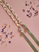 Load image into Gallery viewer, Intertwined Handfasting Cord made from cream, sage and peach coloured strands of satin ribbon, along with gold leaf charms. Set against a pink backdrop with confetti.
