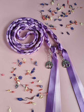 Load image into Gallery viewer, Intertwined Handfasting Cord made from mauve, lilac and lavender strands of satin ribbon, along with silver tree of life charms.  Set against a pink backdrop with confetti.
