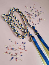 Load image into Gallery viewer, Intertwined Handfasting Cord made from blue, ivory and gold strands of satin ribbon.  Set against a pink backdrop with confetti.
