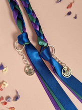 Load image into Gallery viewer, Intertwined Handfasting Cord made of blue, green and purple strands of satin ribbon, along with silver thistle charms.
