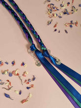 Load image into Gallery viewer, Intertwined Handfasting Cord made of blue, green and purple strands of satin ribbon, along with silver thistle charms.
